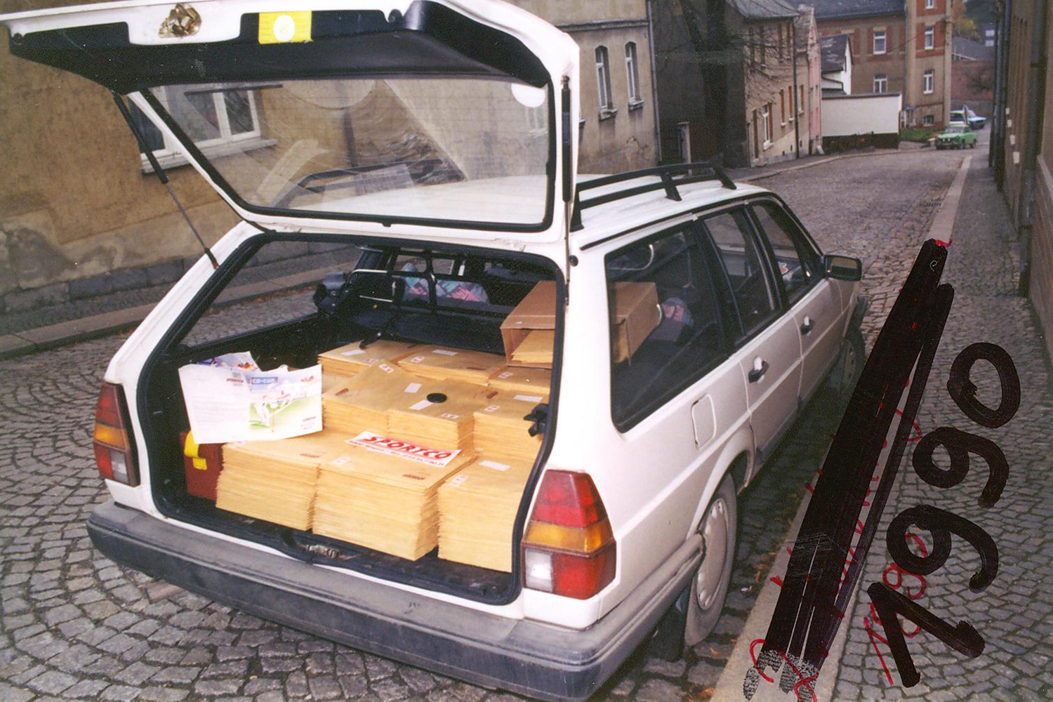Ein weißer Kombi mit offenem Kofferraum, voll mit Breiefumschlägen.